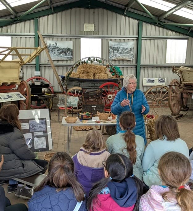 Children sat around in a circle in an arts and crafts room.