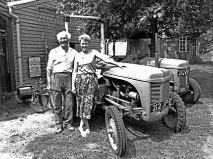 A black and white photo Henry and Madge Jackson in front of a tractor.