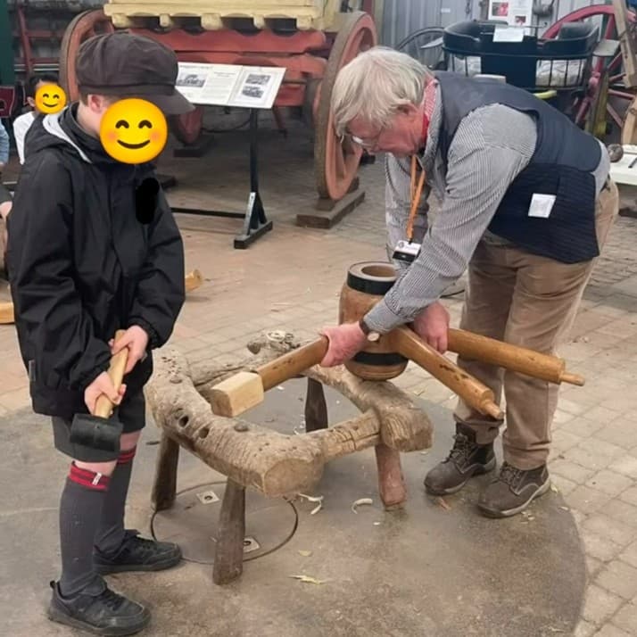 A wheelwright showing children how to make a wheel.